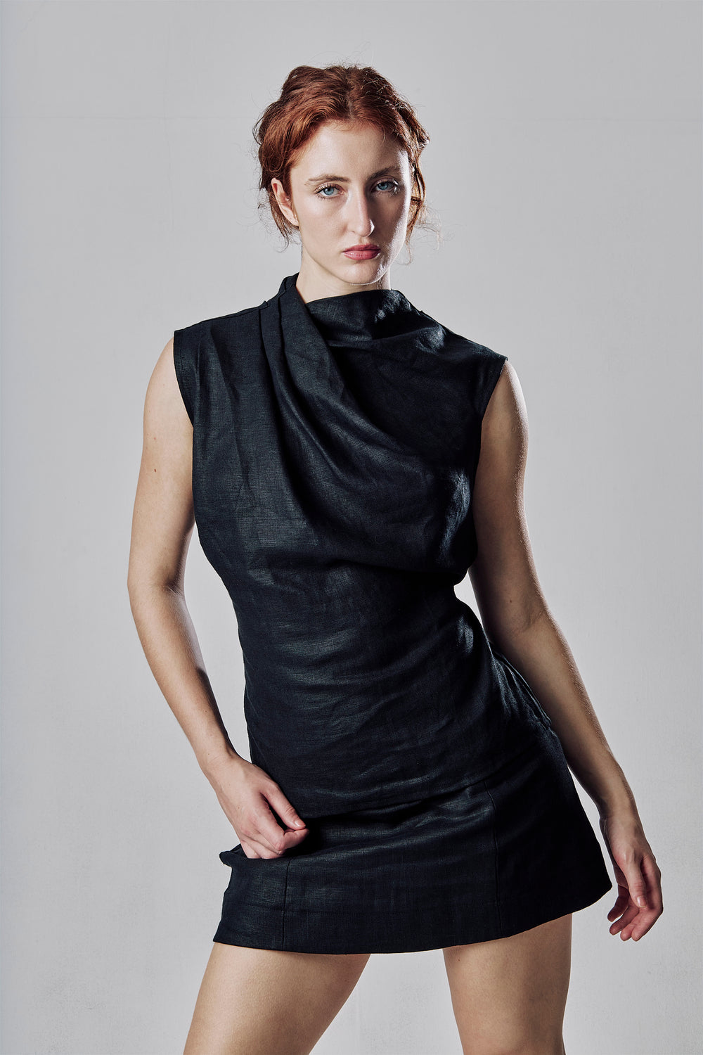 Oxeye Top in black linen, front view showing the draped neckline, worn with the Lily Mini Skirt in black
